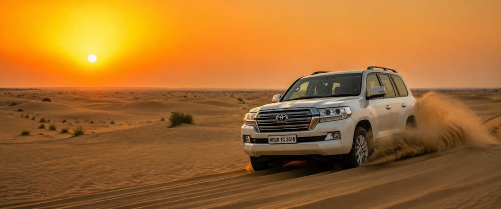 Dubai Desert Safari Guide: Morning vs Evening vs Overnight — Which One Fits Your Trip? 1 A 4x4 Land Cruiser crossing sand dunes in the UAE desert at sunset