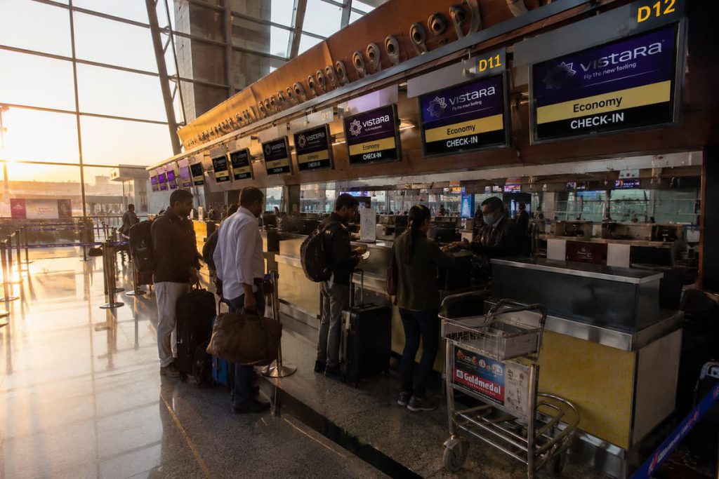Rajkot to Dubai Flight Schedule: Daily, Weekly and Seasonal Timings 2 A photorealistic photo of an airport check-in counter at early morning with warm sunrise light coming through terminal windows, a small queue of travelers with luggage